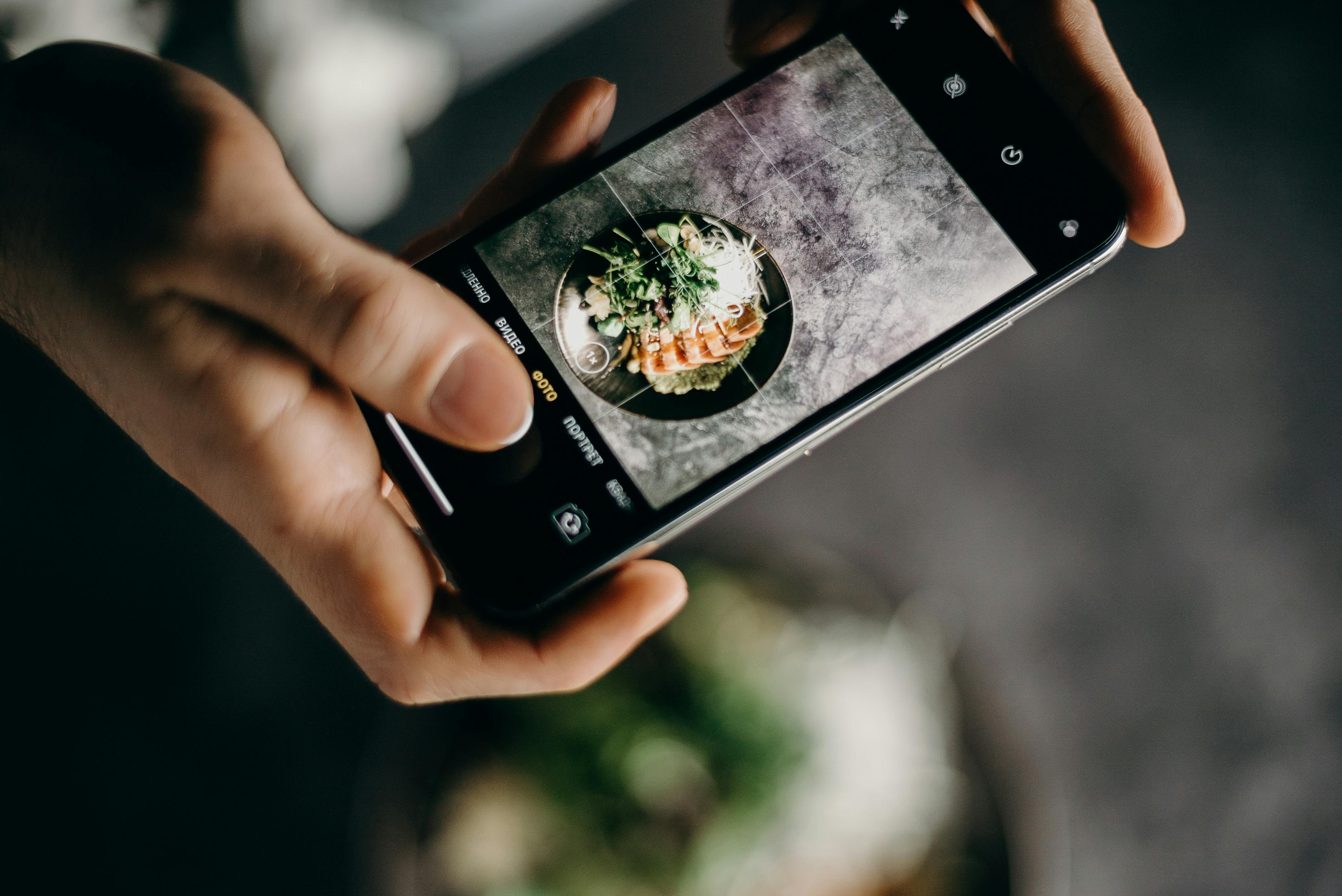 Person photographing delicious Asian dish with a smartphone in a creative setting.